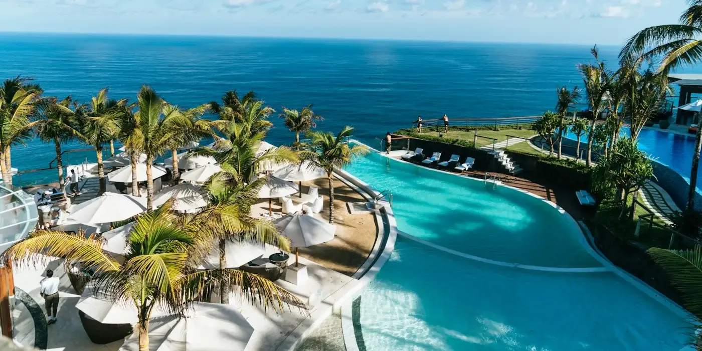 Piscina de un resort con hamacas y palmeras al atardecer