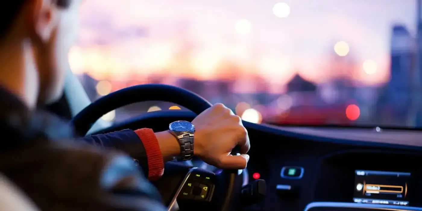Conductor al volante de un coche al atardecer en la ciudad